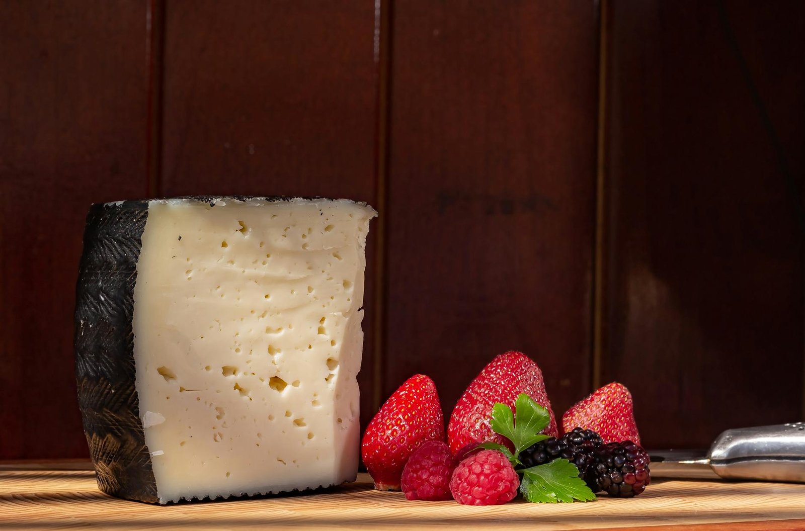 wedge of cheese with fresh berries on a wooden board
