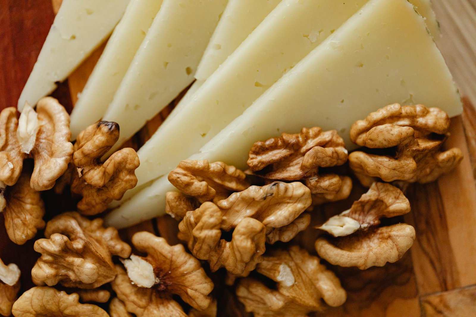 sliced cheese and roasted walnuts on wooden board