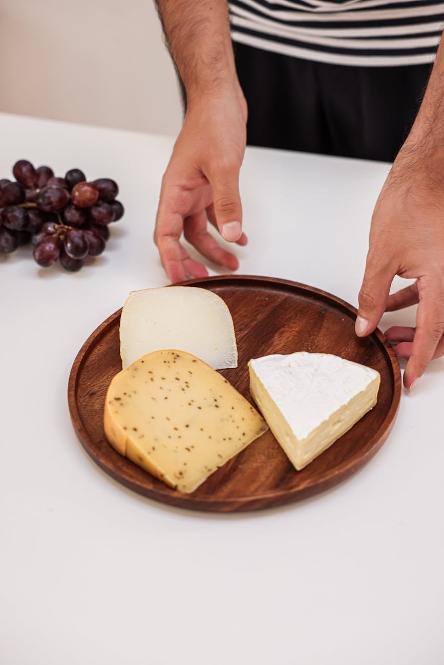a person holding a wooden plate with cheese